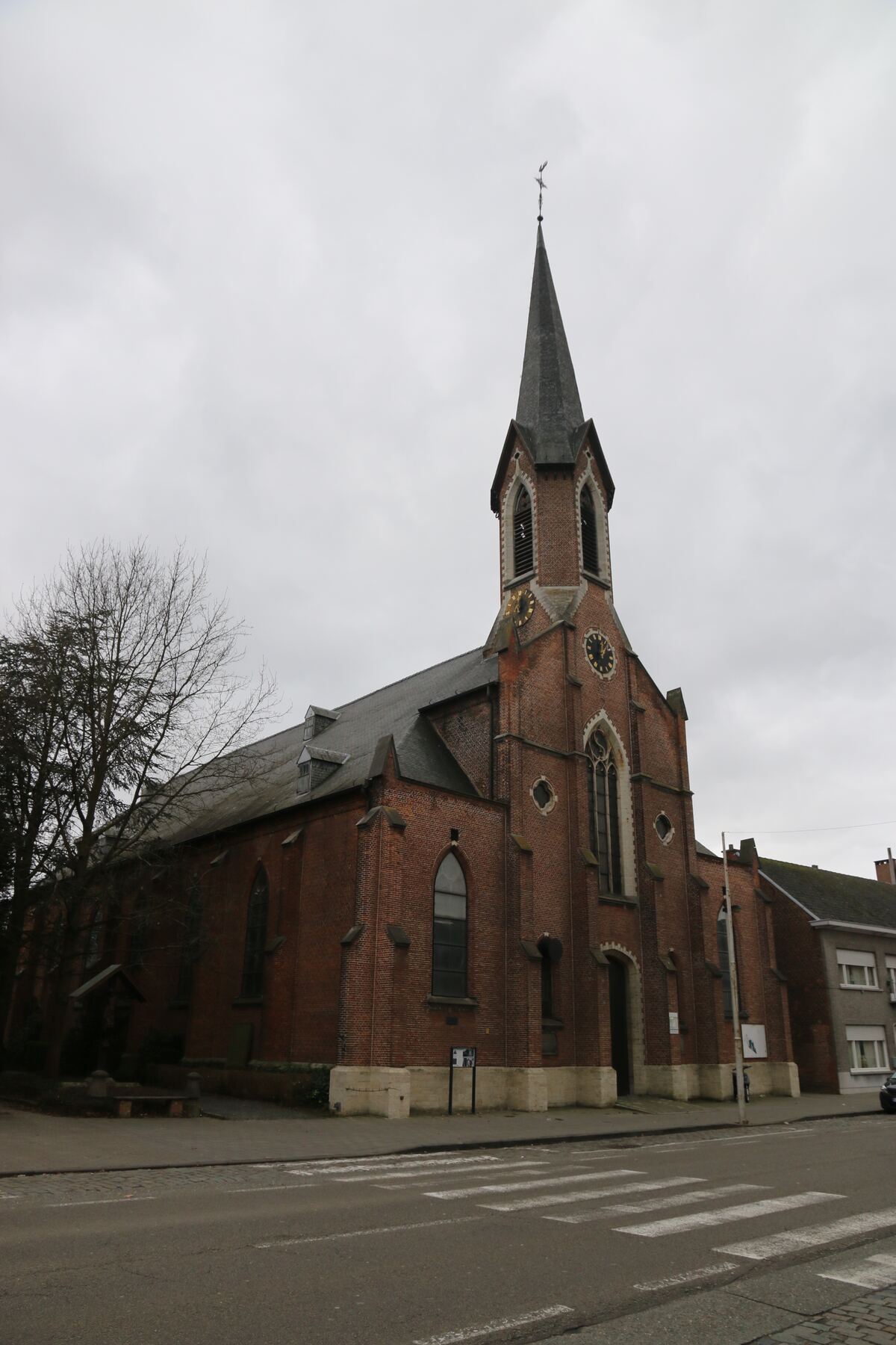 De rode bakstenen Sint-Jan Evangelistkerk van Koningshooikt met haar spitse toren